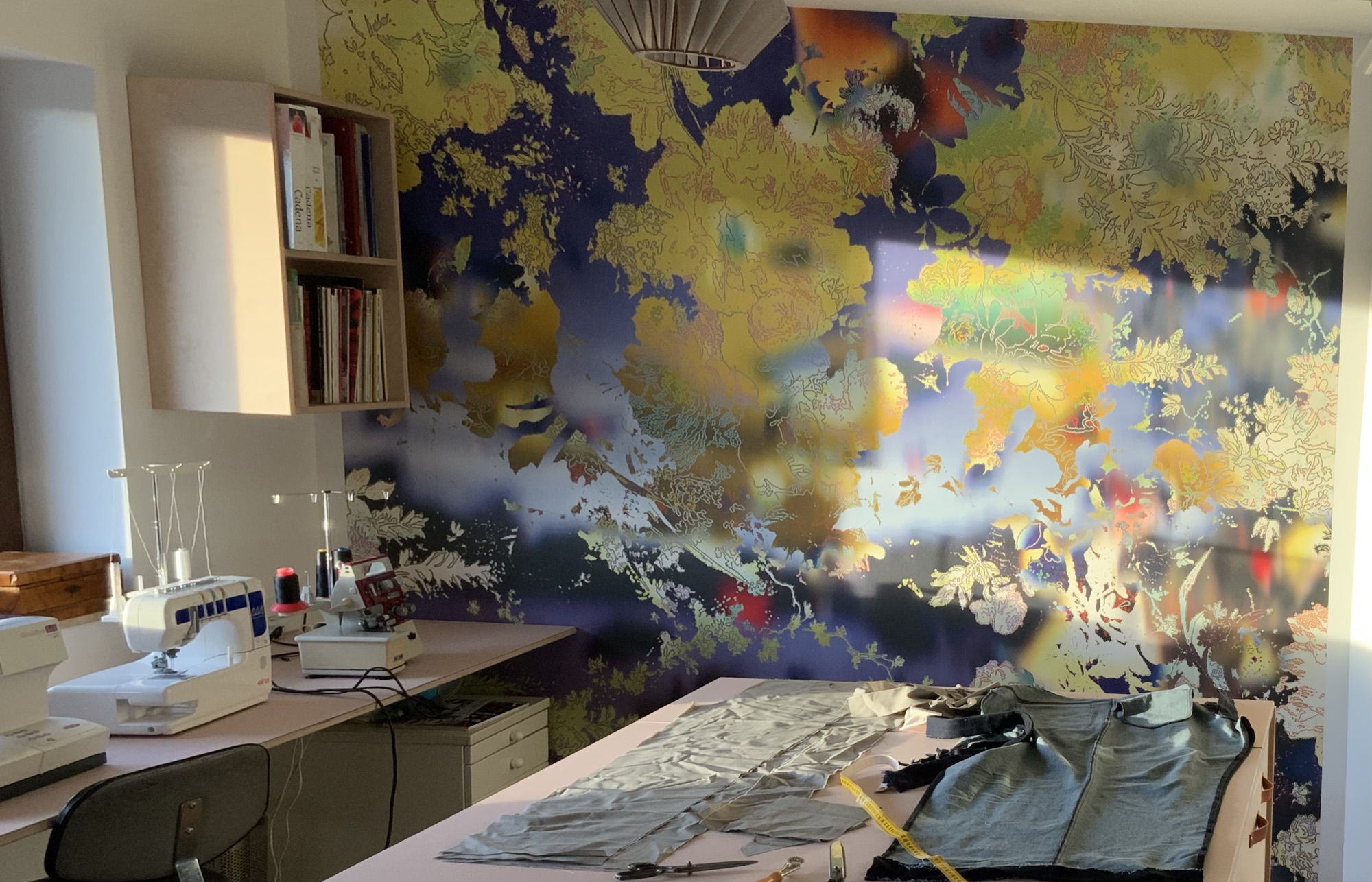 Das Atelier mit Nähmaschinen, Zuschneidetisch und der bunten Wandtapete